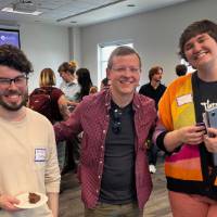 Three event attendees, standing together and posing for photo